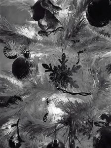 black and white close up of ornaments on a white christmas tree.
