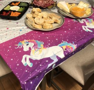 table cloth with stars and a unicorn with a rainbow mane and tail on a purple background.