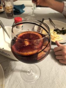 Crytsal wine glass filled with red wine sangria, with an orange slice floating on top