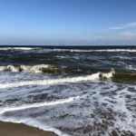 small, choppy waves crashing on the beach on a sunny day in November