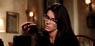 Sandra Bullock from Practical Magic. Wearing Glasses, concentrating on a spell