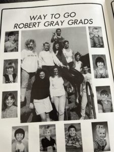 A highscool year book add for a the graduating group of students from the same elementary school. The largest central picture is of all the older students. It is surrounded by small grade school photos of each student.
