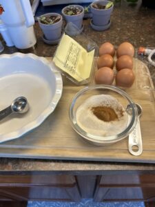 Collection of items to make pie. Pie plate, carton of eggs, dry ingredients - sugar and spices.