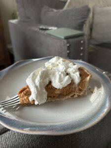 One slice of pumpkin pie with whipped cream on top.